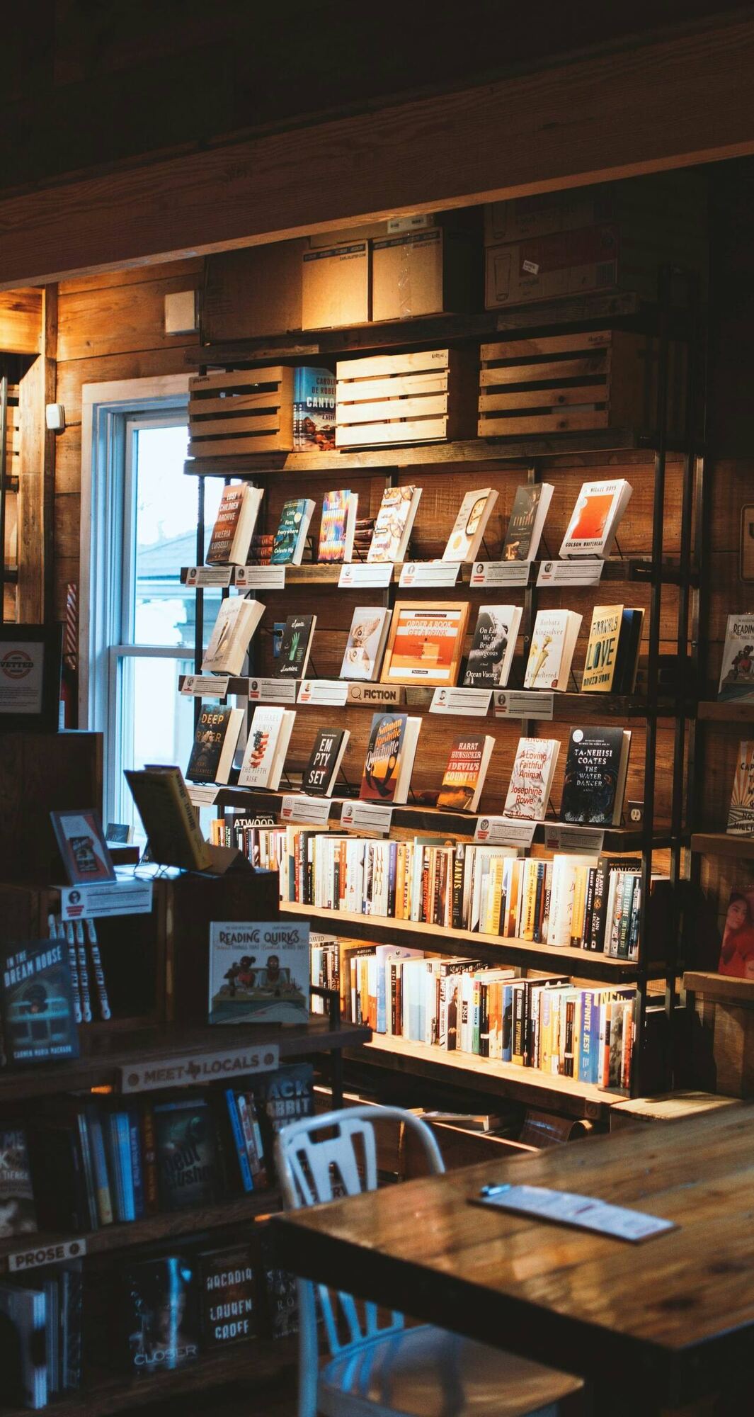 Baldas de libros de frente y una mesa de madera junto a la ventana